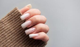 Female hand with winter nail design on grey background photo