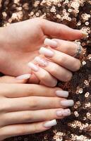 Woman showing stylish nails with red glitter on sequins background photo