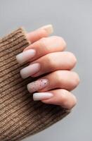 Woman showing manicure with brown sleeve on grey background photo