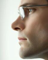 Man with glasses thoughtfully gazes in profile against a light background, showing deep reflection photo