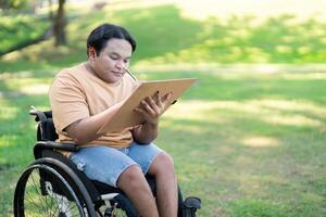 Disabled artist in wheelchair concentrating on sketching nature in a tranquil park photo
