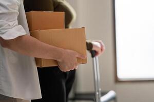 Couple relocating together, carrying moving boxes while preparing to settle into their new home photo