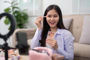 Beauty broker applying eyeshadow with a brush while showcasing her palette in a live broadcast photo
