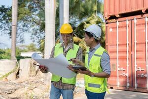 Engineers reviewing logistics plans and collaborating at a shipping container site photo