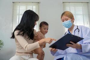Pediatrician showing medical records to mother and baby during a check-up. photo