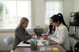Diverse business team collaborating at desk with tablets and notes. photo