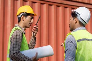 Logistics engineer communicating via walkie-talkie while discussing plans. photo