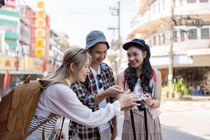 Diverse group of friends reviewing photos together on a bustling street, capturing travel memories and enjoying their time in the city.
