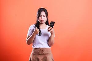 A person with a phone giving a thumbs up on an orange background stands in the middle of the frame photo