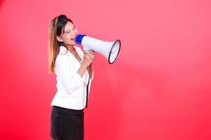 A woman wearing a white blazer and a black skirt is speaking into a white megaphone, the figure is isolated on a red background photo
