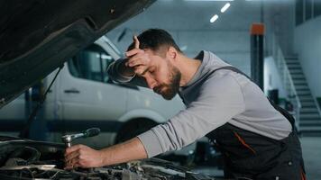 Caucasian mechanic in uniform repairing engine fixing motor inside open bonnet automobile professional auto service male vehicle engineer repairman man using wrench tool car maintenance in workshop photo