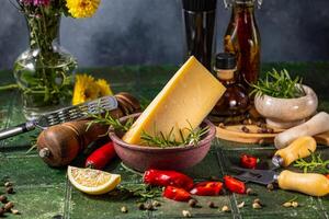 Block of hard cheese with rosemary sprigs and assorted spices for cooking photo