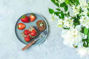 Chocolate roll cake with fresh strawberries and white flowers photo