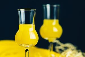 Two stemmed glasses with yellow liquor on a dark background photo