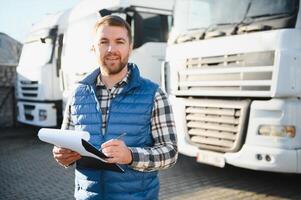 Truck driver checking shipment list while standing on parking lot of distribution warehouse. photo