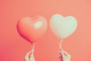 Woman holding two heart shaped balloons on coral background for valentine's day photo