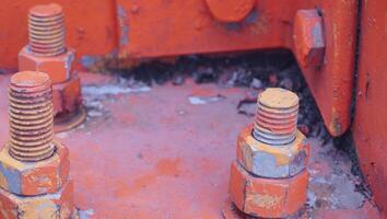 a close up of some bolts and nuts on an orange machine photo