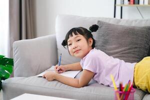 A little girl is happily creating art by drawing and coloring with colored pencils on a piece of paper. photo