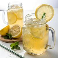 Two mason jars filled with a light yellow beverage, garnished with lemon slices and mint leaves photo