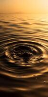 Rippling water surface reflecting golden hues, with a central disturbance creating circular waves photo