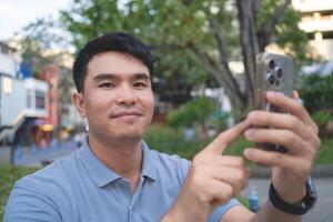 A man is taking a picture of himself on his cell phone. He is smiling and pointing at the camera photo
