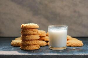 Milk in glass and cookies a black table, closeup of photo