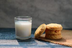 Milk in glass and some cookies on the table, closeup of photo