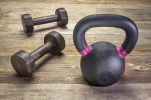small iron kettlebell and dumbbell on rustic wood photo