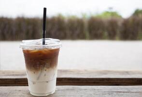 Iced of latte coffee cup on wooden backdrop grass nature background. Copy space for text photo