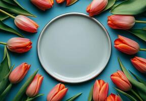 Colorful tulips surround a blank plate on a blue background for a vibrant spring display photo