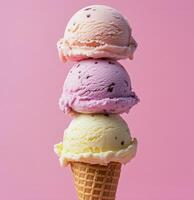 Delicious ice cream cone with three colorful scoops stacked high on a pink background photo