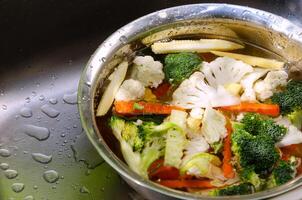 Vegetables at kitchen sink, washing fresh vegetables water with colorful fresh vegetables in the background, emphasizing healthy eating and cleanliness. photo