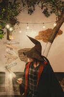 Man dressed in Hogwarts-inspired attire stands under string lights at a magical-themed location photo