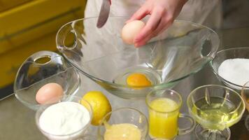 chef cracking egg with knife and separating yolks from whites, putting egg whites into bowl and egg yolks into glass video