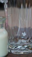 pouring milk from bottle to glass fresh organic beverage calcium nutritious slow motion. Healthy dairy product nourishment adding stream for breakfast with corn flakes and apple video