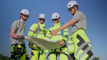 Team of technicians walking through a wind farm, showcasing teamwork and safety practices in renewable energy work. video