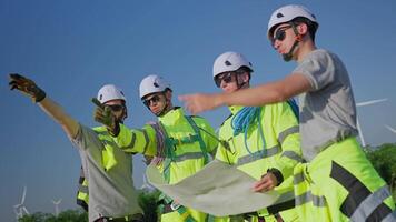 Team of technicians walking through a wind farm showcasing teamwork and safety energy work. video