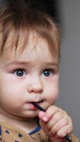 Funny cute baby boy playing with a cord chewing it. Close up portrait of a child shoving things into mouth when teeth grow. Vertical video
