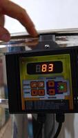 Male hand switching on the button on the centrifuge apparatus. Man presses one more button to increase the speed of work of equipment. Close up. Vertical video