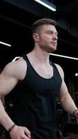 Young handsome man training on a simulator. Athletic guy is running on a modern treadmill in the gym. Slow motion. Vertical video