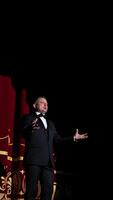 Senior man in costume on stage in darkness. Actor man in selective light on stage during the performance in the theater. Vertical video