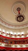 Selective focus on empty rows with red velvet seats in theater hall. Rows with empty chairs. No people because of covid-19. Vertical video