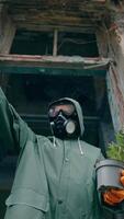 Ecological problems. Ecologist in protective gloves and suit pulling out fresh flowers from flower pot. Abandoned place. Biological attack. Vertical video
