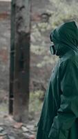 Man in a special suit in destroyed place. Human in chemical protective suit in ruined place. Post-apocalyptic world concept. Real background of abandoned place. Vertical video