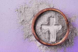 Cross imprint in gray ash on purple background. Ash Wednesday photo