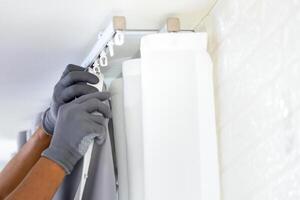 Repairman installs a curtain rod and hangs curtains in the house, Worker hanging window curtain photo