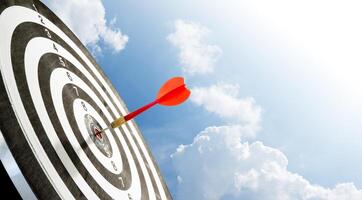red dart on target with blue sky background photo