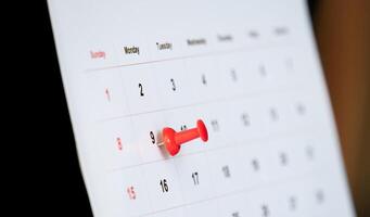 red push pin stuck on calendar background photo