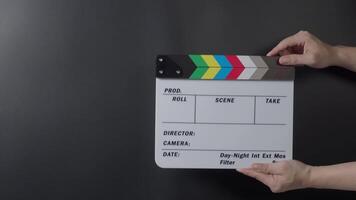 A classic clapperboard or film slate being held and hit against a dark background. Symbolizes filmmaking vdo production movie filming and creative storytelling in the entertainment industry. video