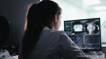 In Control Room Doctor, Radiologist Watching Diagnosis Procedure and Monitors Showing Brain Scans Results, In the Background Patient Undergoes MRI or CT Scan Procedure. video